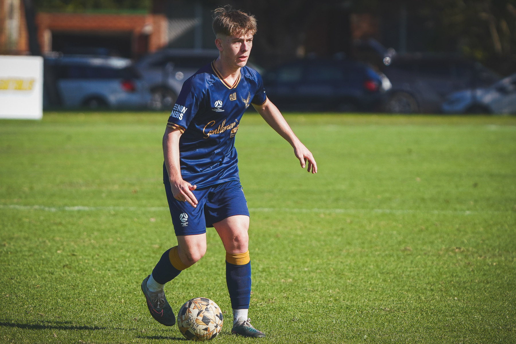 A soccer player in a blue uniform is on the field, focused on controlling the ball.