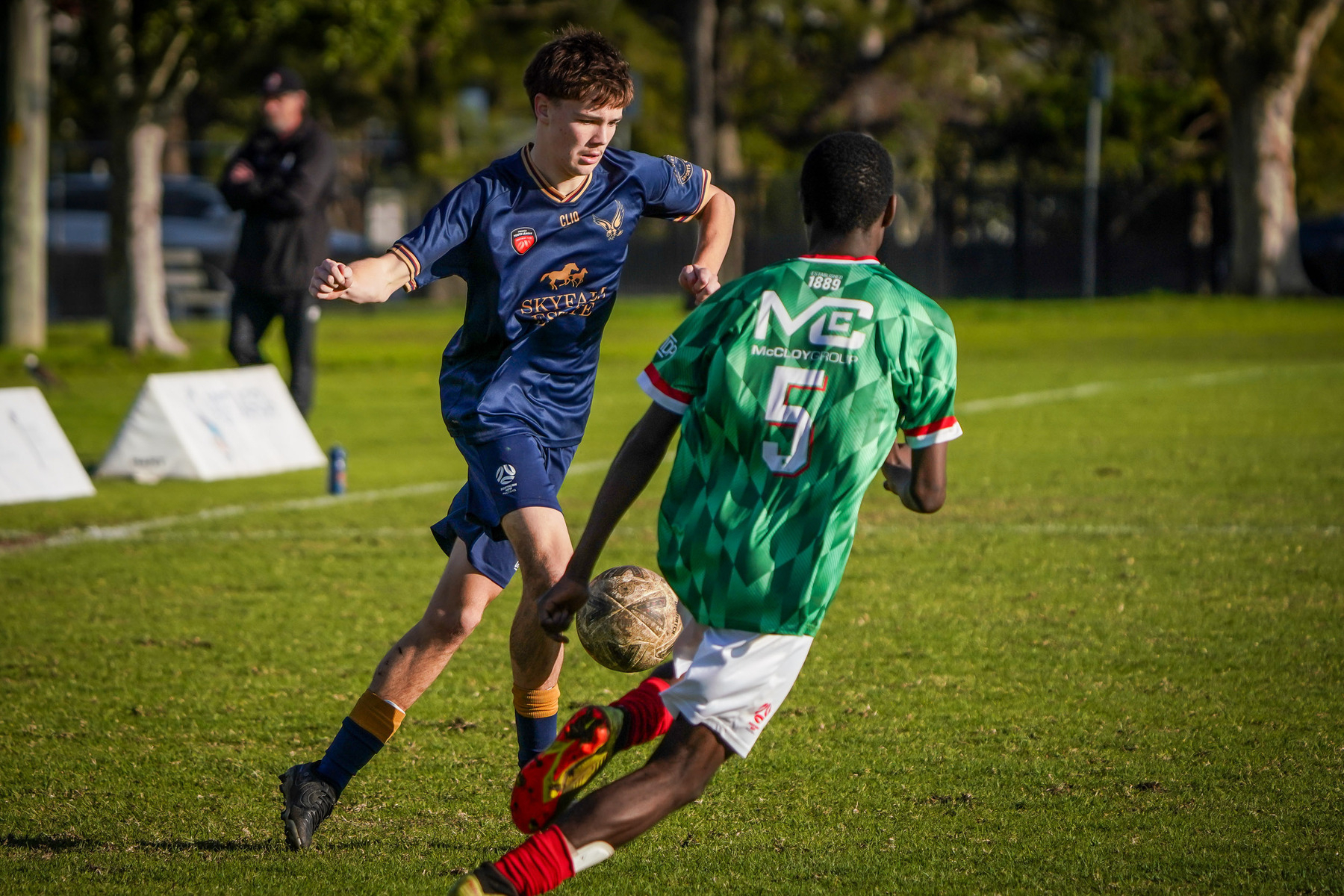 Two soccer players are in action on a field, with one attempting to defend against the other.