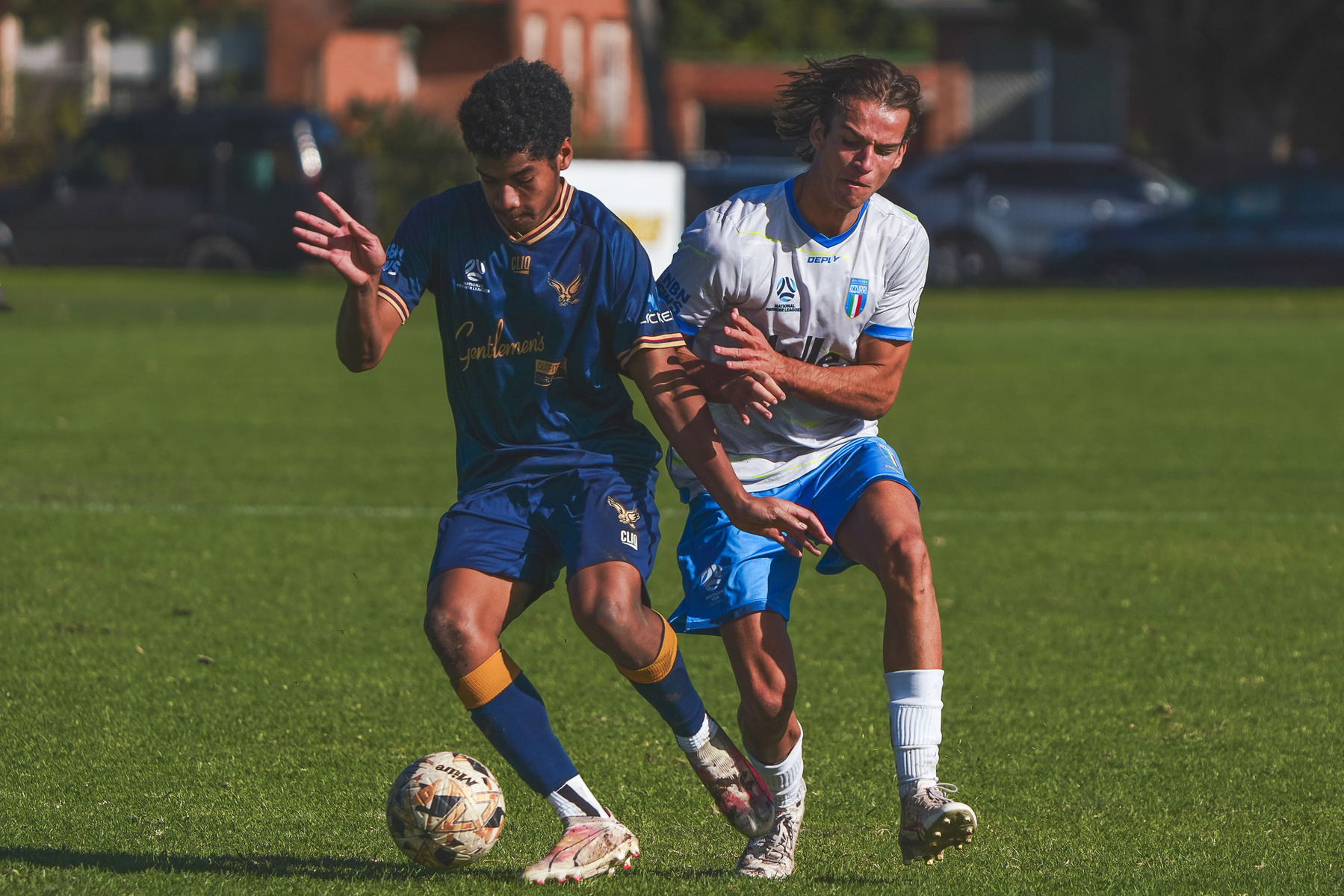 Two soccer players are competing for the ball on a grassy field.