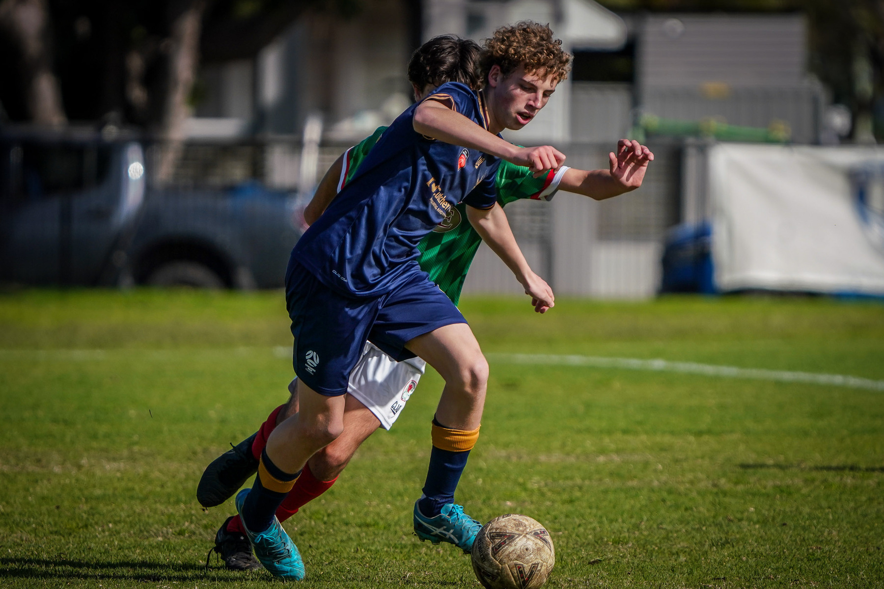 Two soccer players are actively competing for control of the ball on a grass field.