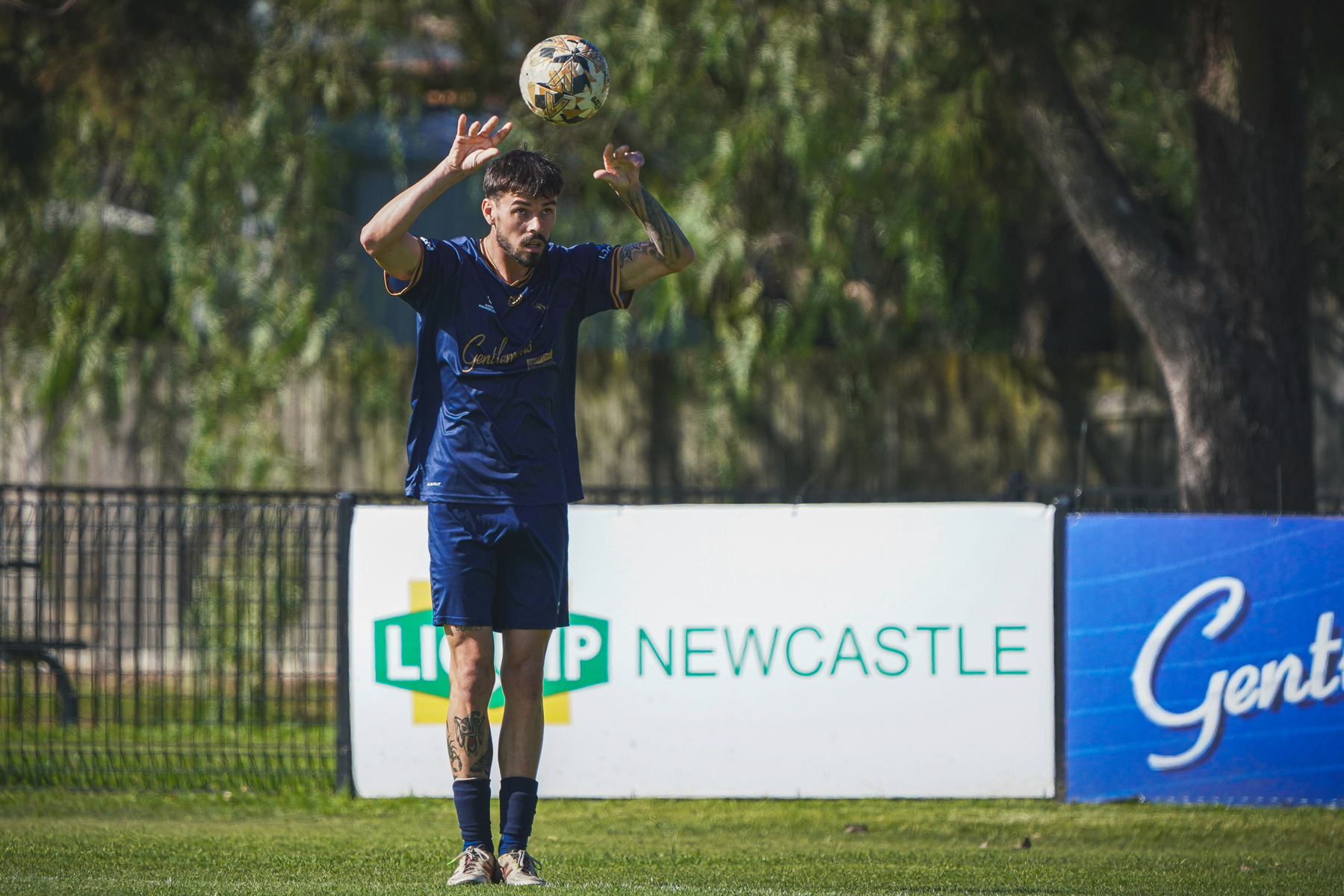 A soccer player is preparing to throw a ball in during a match on a grassy field.