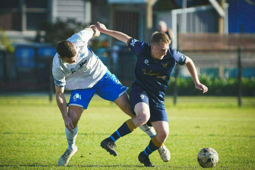 Two soccer players are competing for the ball on a grassy field.