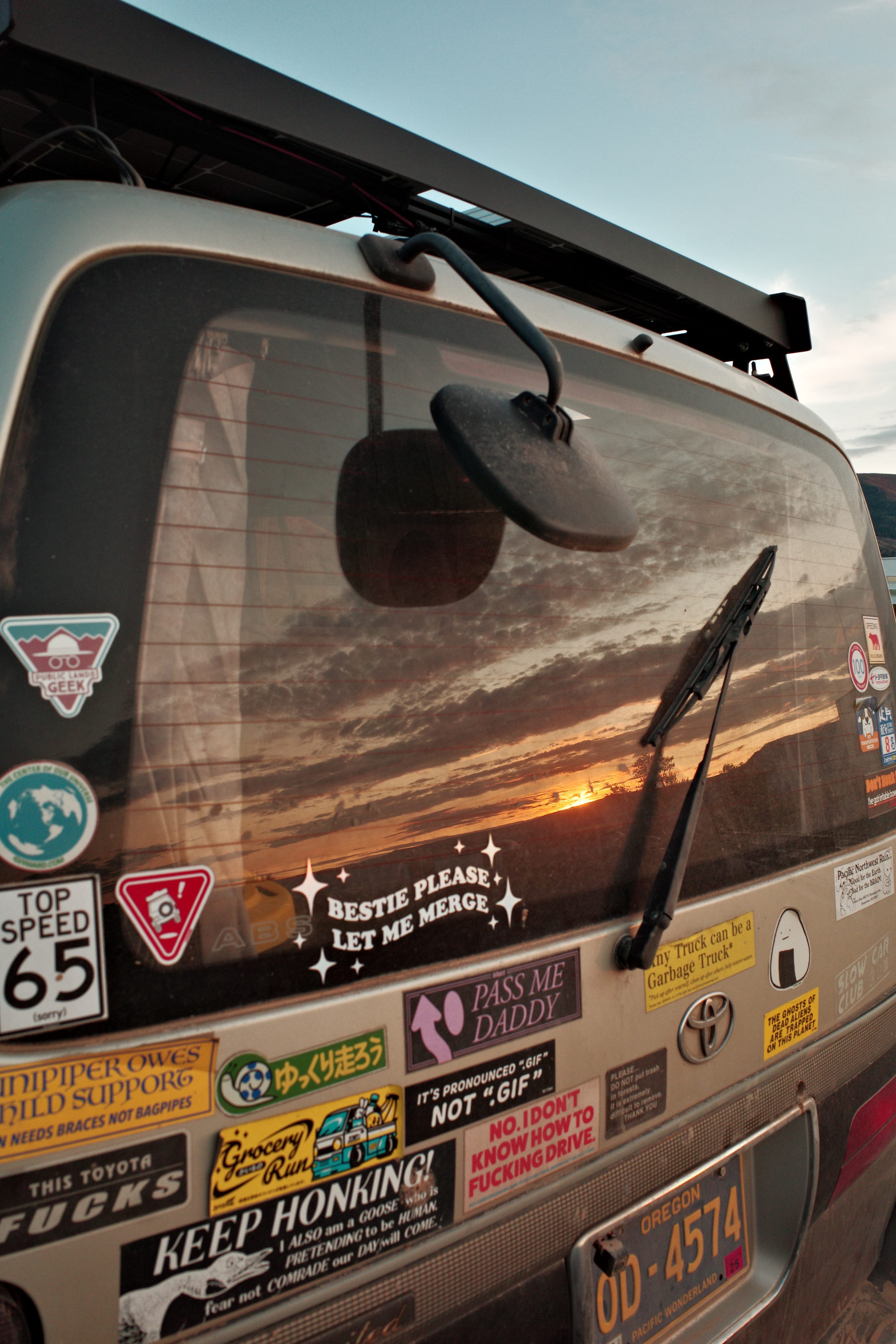 A photo of the back of a HiAce van captures the sunset in it’s rear window.