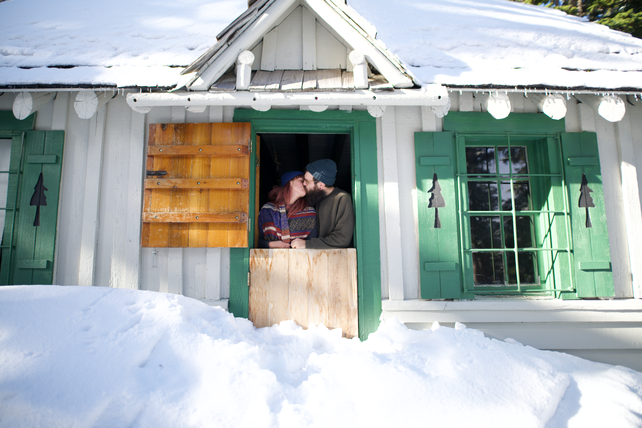 A couple is sharing a kiss while standing at the window of a snow-covered cabin. (Mt. Hood, 2020)