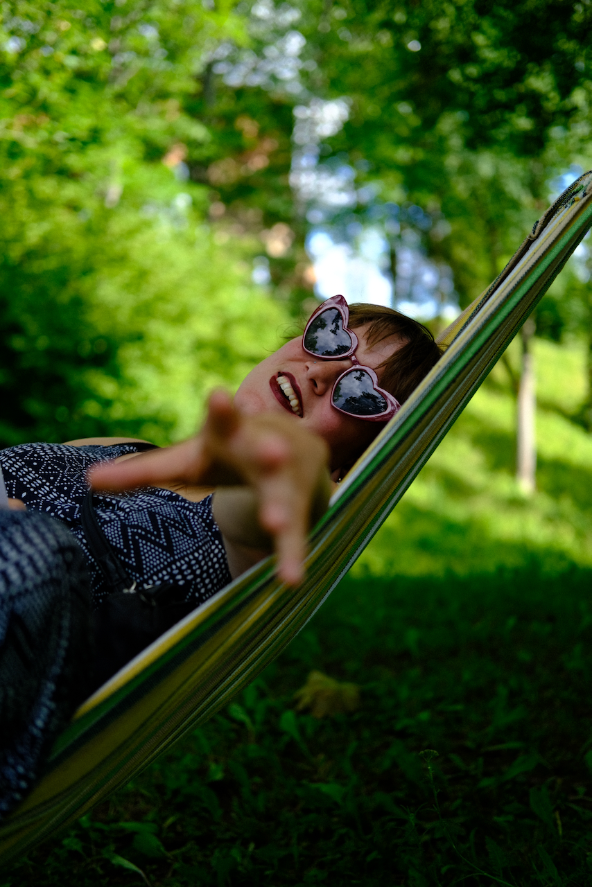 A person wearing heart-shaped sunglasses relaxes in a hammock surrounded by lush greenery. (Estonia, 2022)