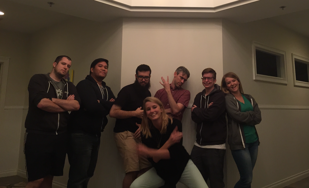 Seven people from the early Zapier support team posing together in a meeting room, one crouching in front of the group.