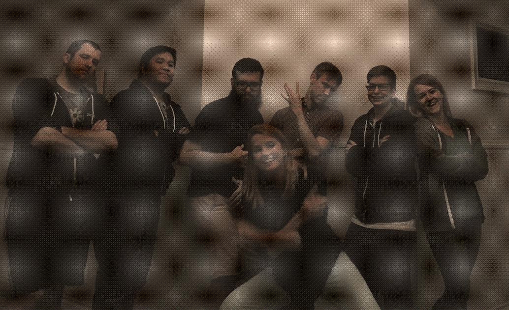 Seven people from the early Zapier support team posing together in a meeting room, one crouching in front of the group.