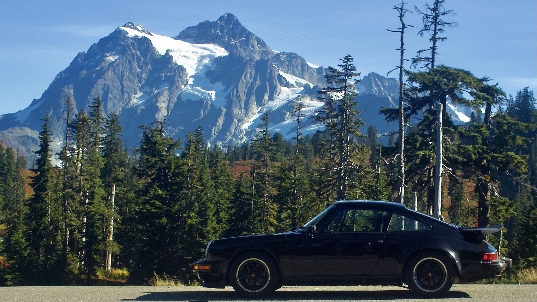 A black vintage 911 in front of a dramatic mountain vista