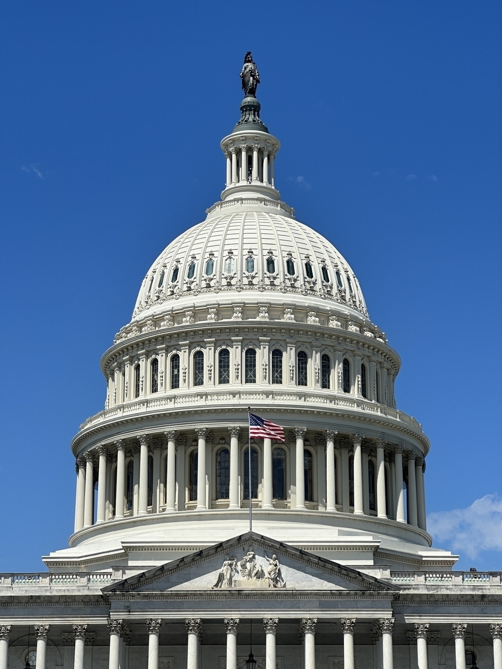 The United States Capitol building's dome is captured against a clear blue sky.