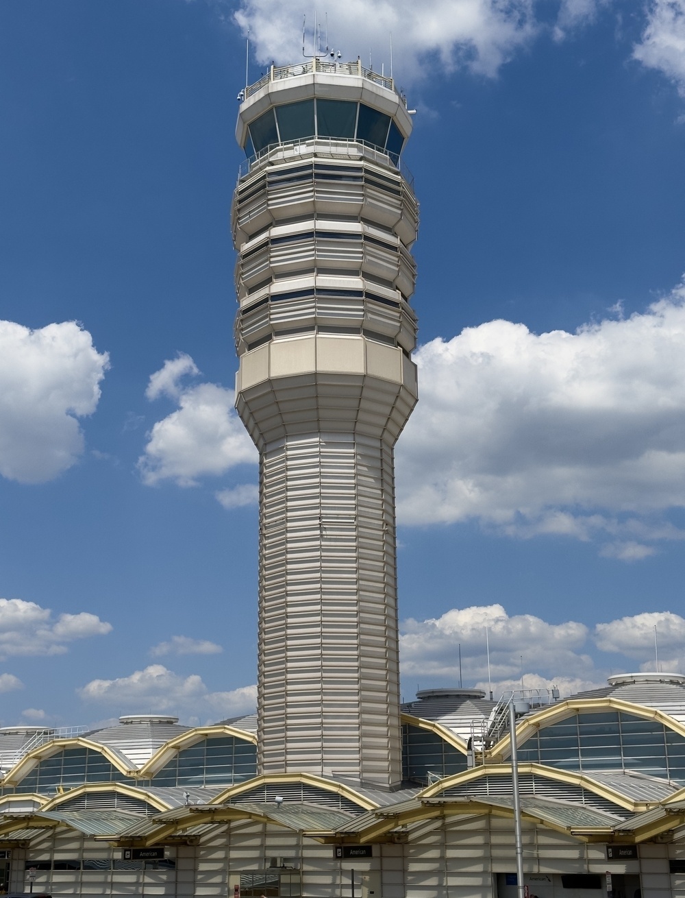 Reagan control tower stands against a backdrop of a blue sky with scattered clouds.