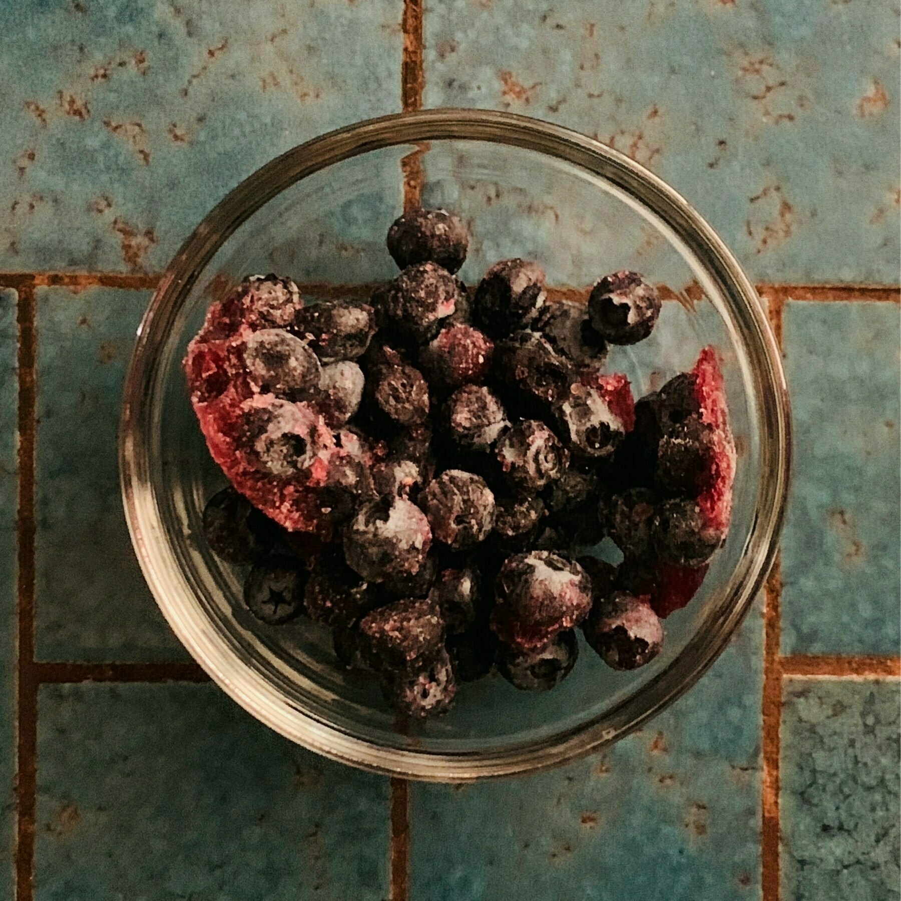 bowl of frozen blueberries on a blue counter