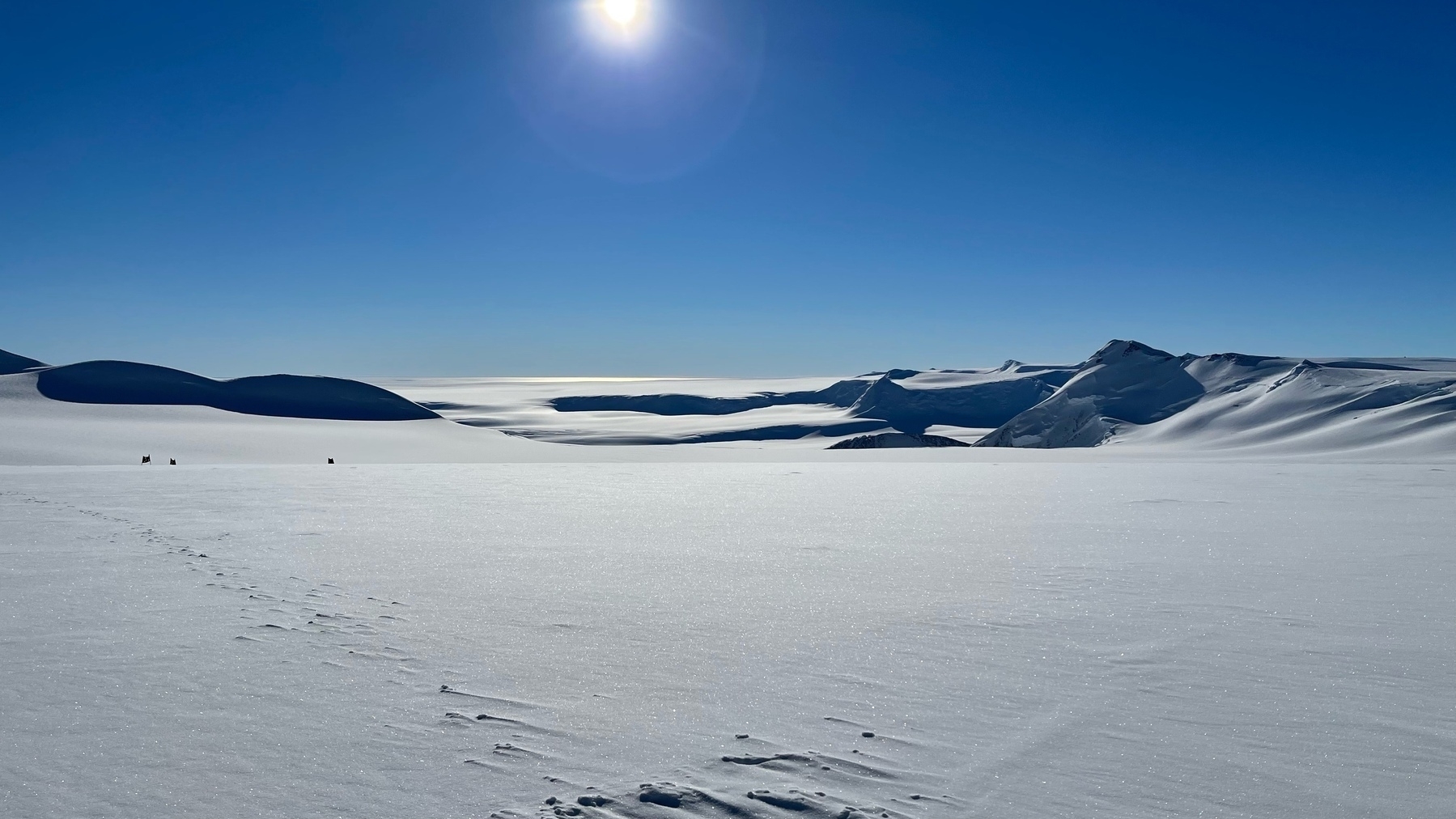 ice field with distant mountains and deep blue sky