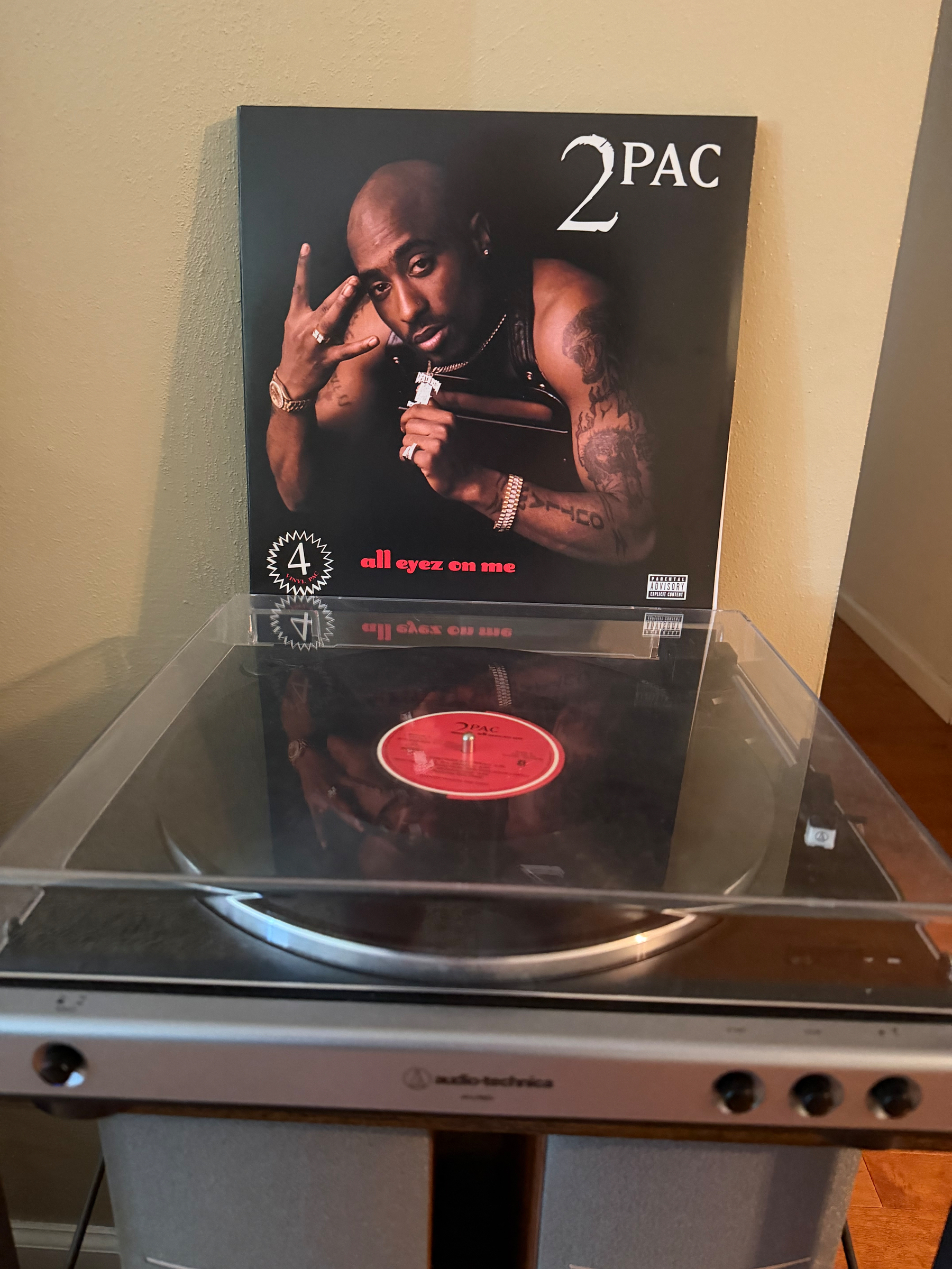 A vinyl record player is shown with a copy of 2Pac's album All Eyez on Me displayed behind it.