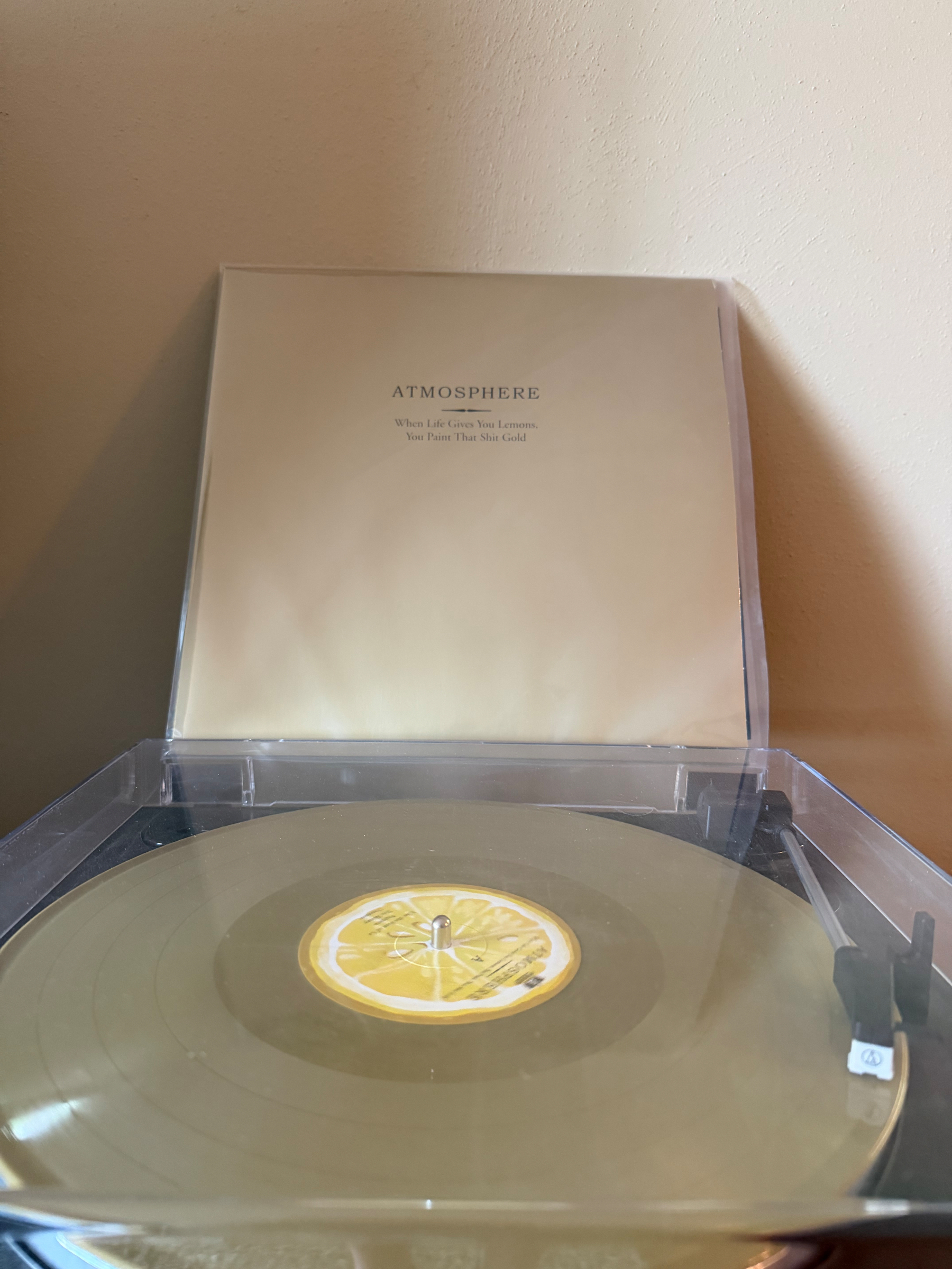 A yellow vinyl record labeled Atmosphere is playing on a turntable, with its cover displayed behind it.