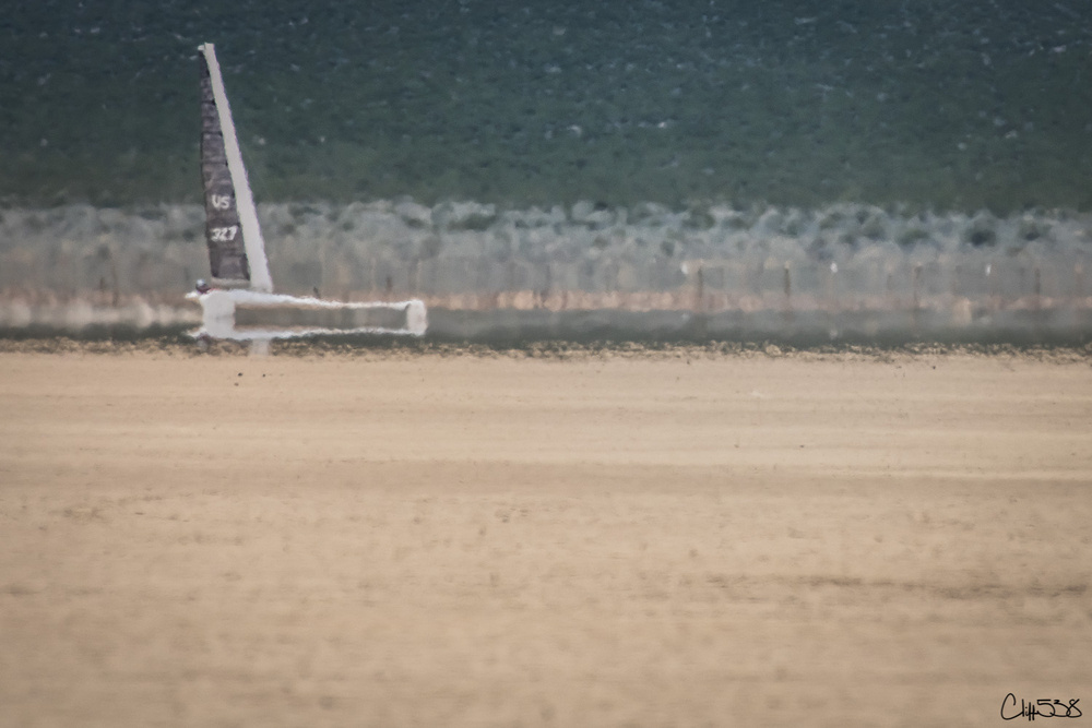 A sailboat appears distorted by a mirage effect on a barren plain.