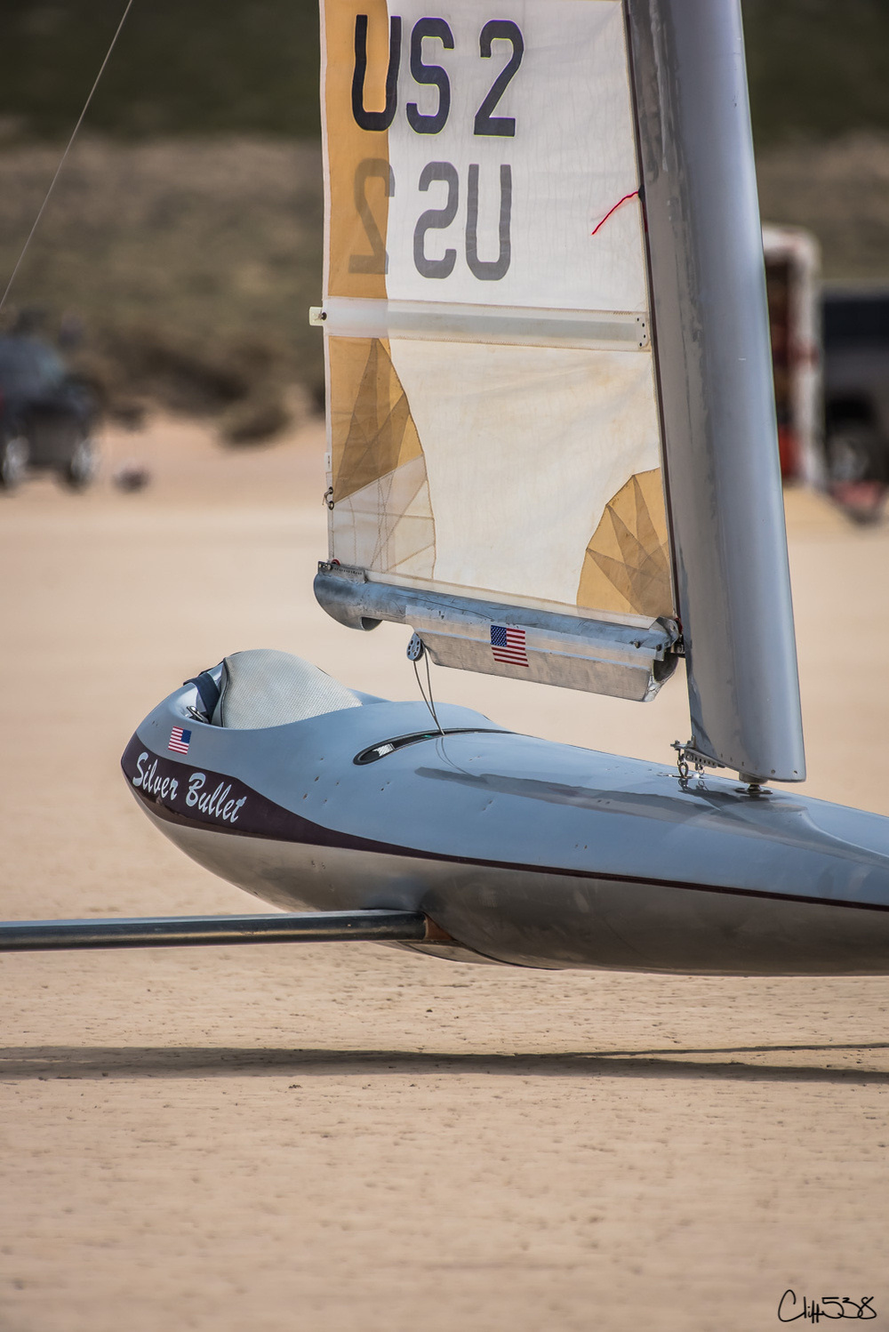 A land yacht named Silver Bullet with a sail labeled US 2 is gliding across a sandy surface.