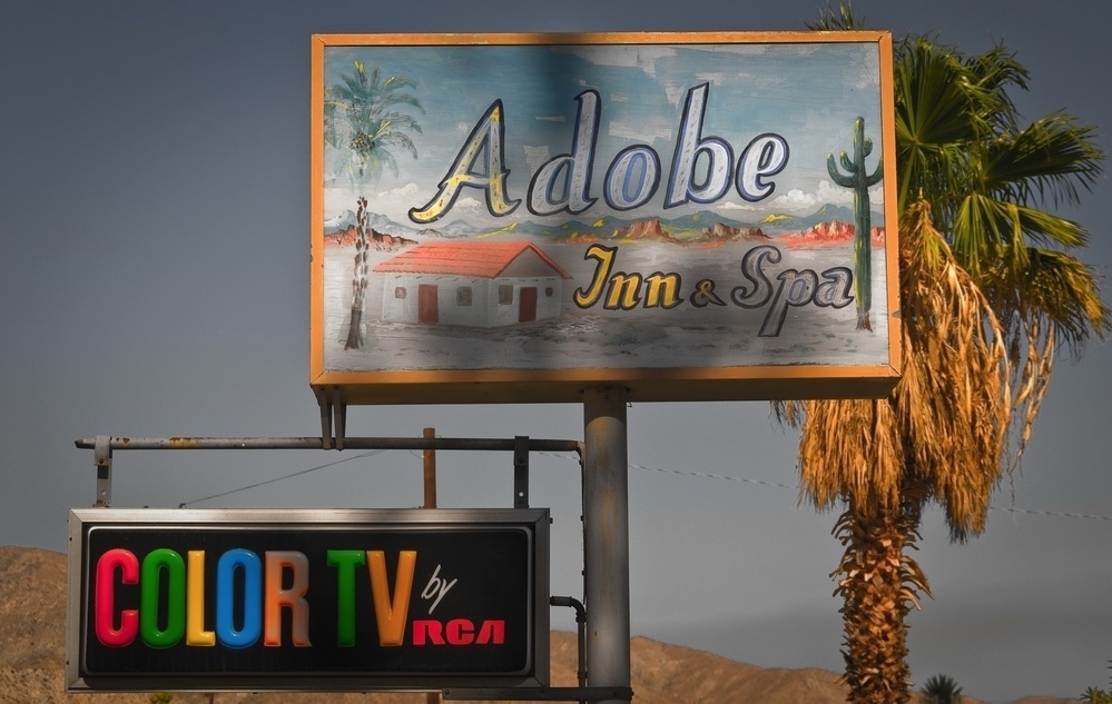 A vintage sign for Adobe Inn & Spa with a landscape painting is paired with another sign advertising COLOR TV by RCA.