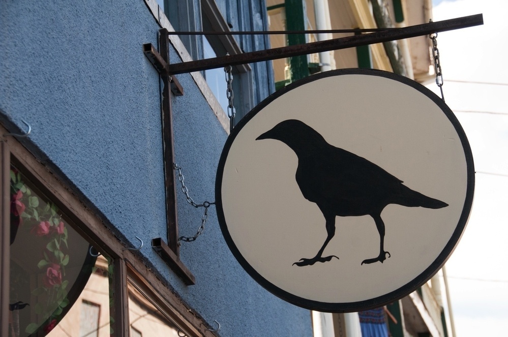 A circular sign featuring a silhouette of a crow is mounted on a building's exterior.