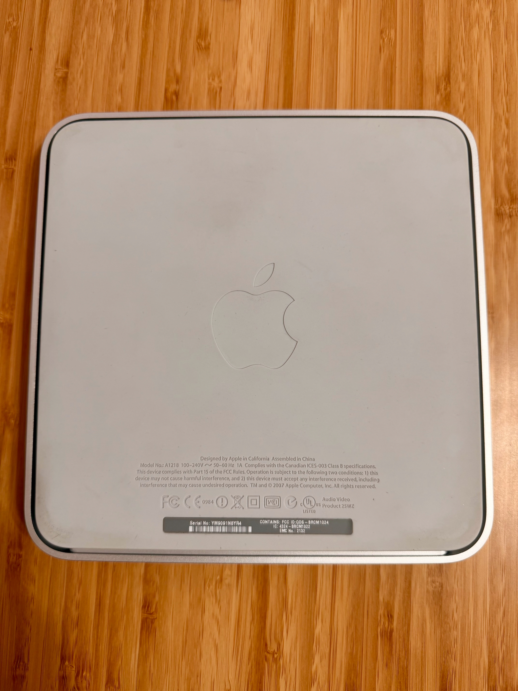 A silver Apple device with an Apple logo is placed on a wooden surface.