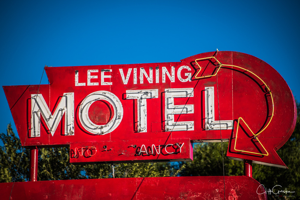 A bright red vintage sign for the Lee Vining Motel features large letters and a neon arrow.