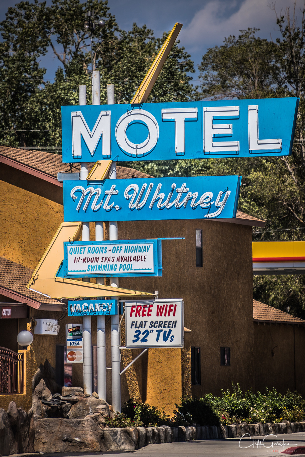 A vintage-style sign advertises the Mt. Whitney Motel, highlighting amenities such as free WiFi, flat screen TVs, and a swimming pool.