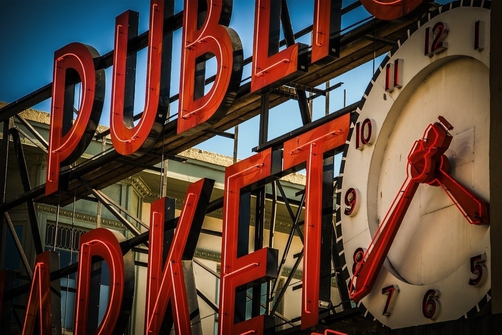 A sign with large red letters saying PUBLIC MARKET is positioned next to an old-fashioned clock.