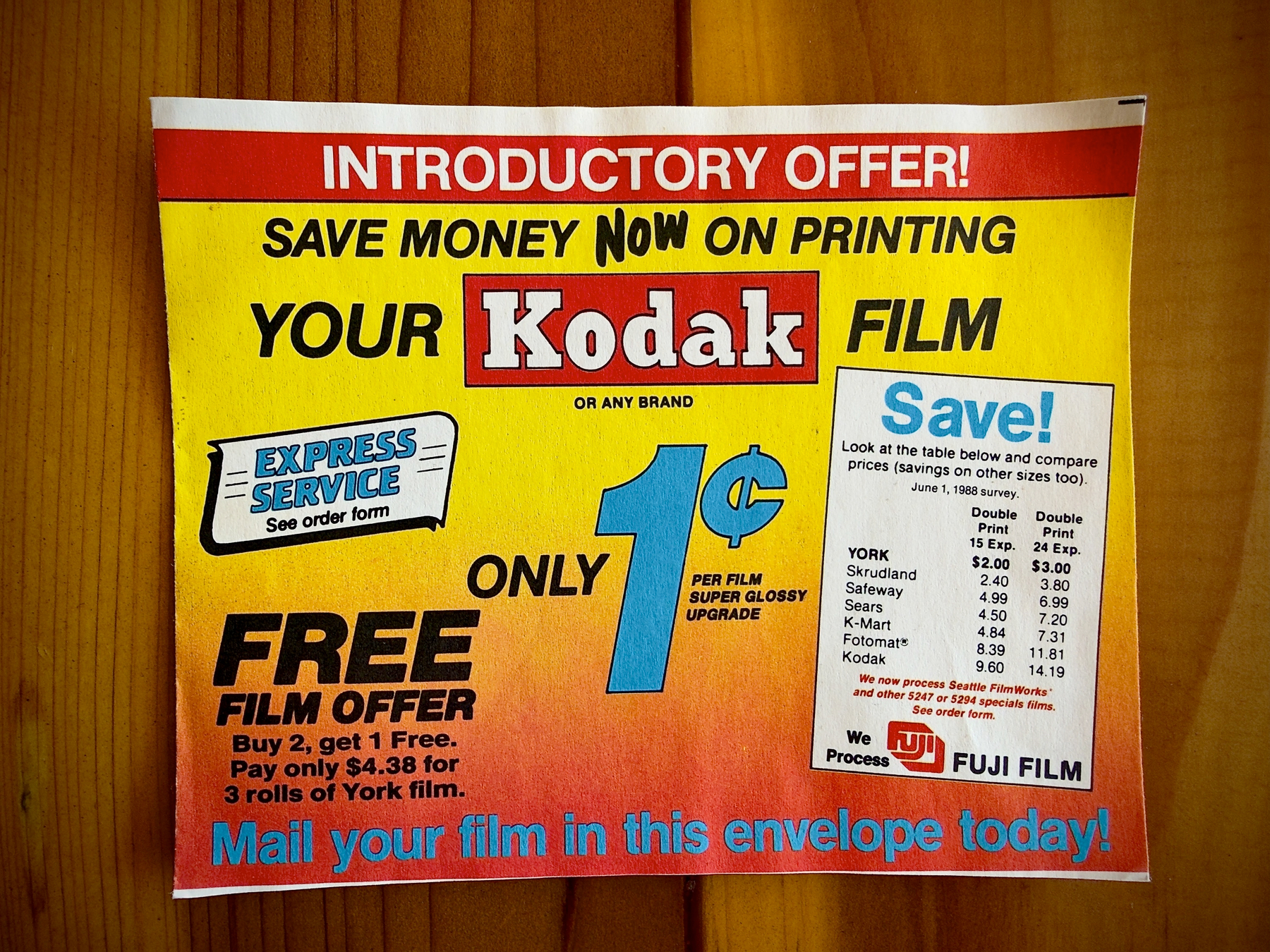 Auto-generated description: An advertisement promotes an introductory offer for Kodak film printing with a special price of 1 cent per film, including a free film offer and express service, encouraging customers to mail their film in the provided envelope.