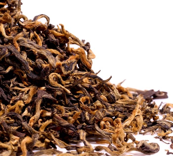 Auto-generated description: A close-up of a pile of dried loose-leaf tea with a mix of dark brown and golden leaves is shown.