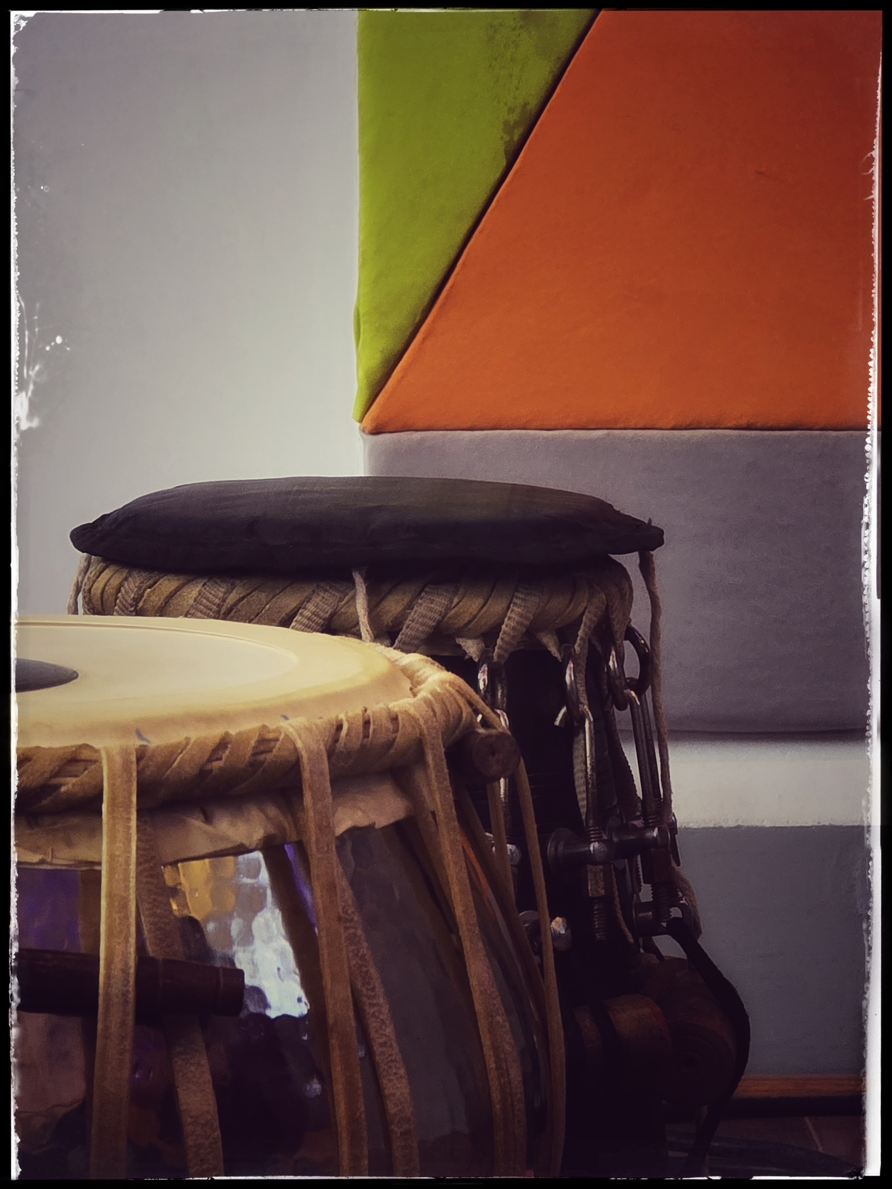 A pair of traditional drums is positioned in front of a colorful, geometric wall backdrop.