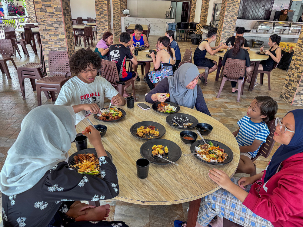 A group of people is enjoying a meal together at a round table in a casual dining setting.