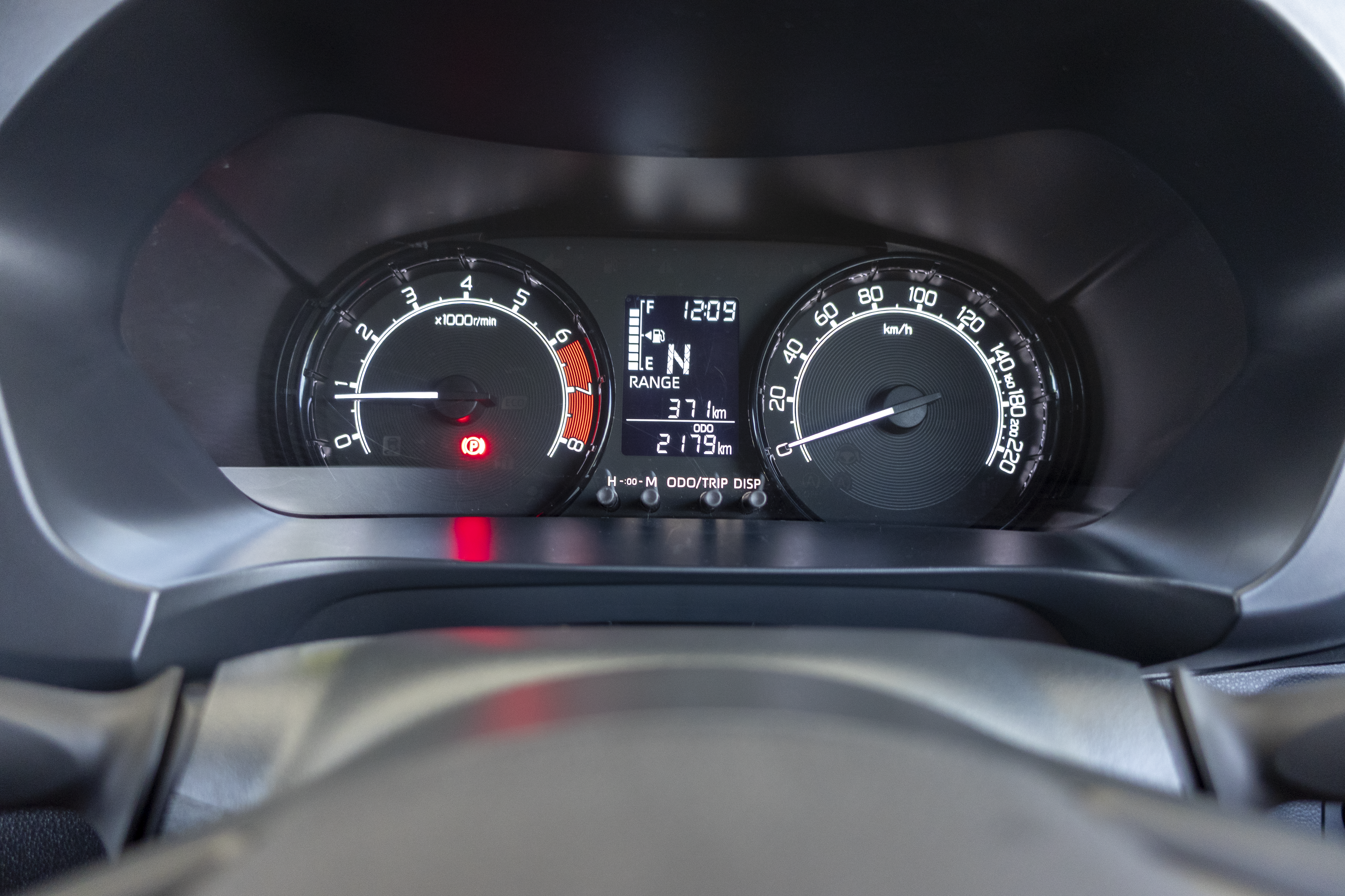 A car dashboard displaying the speedometer, tachometer, fuel gauge, odometer, and other digital indicators.