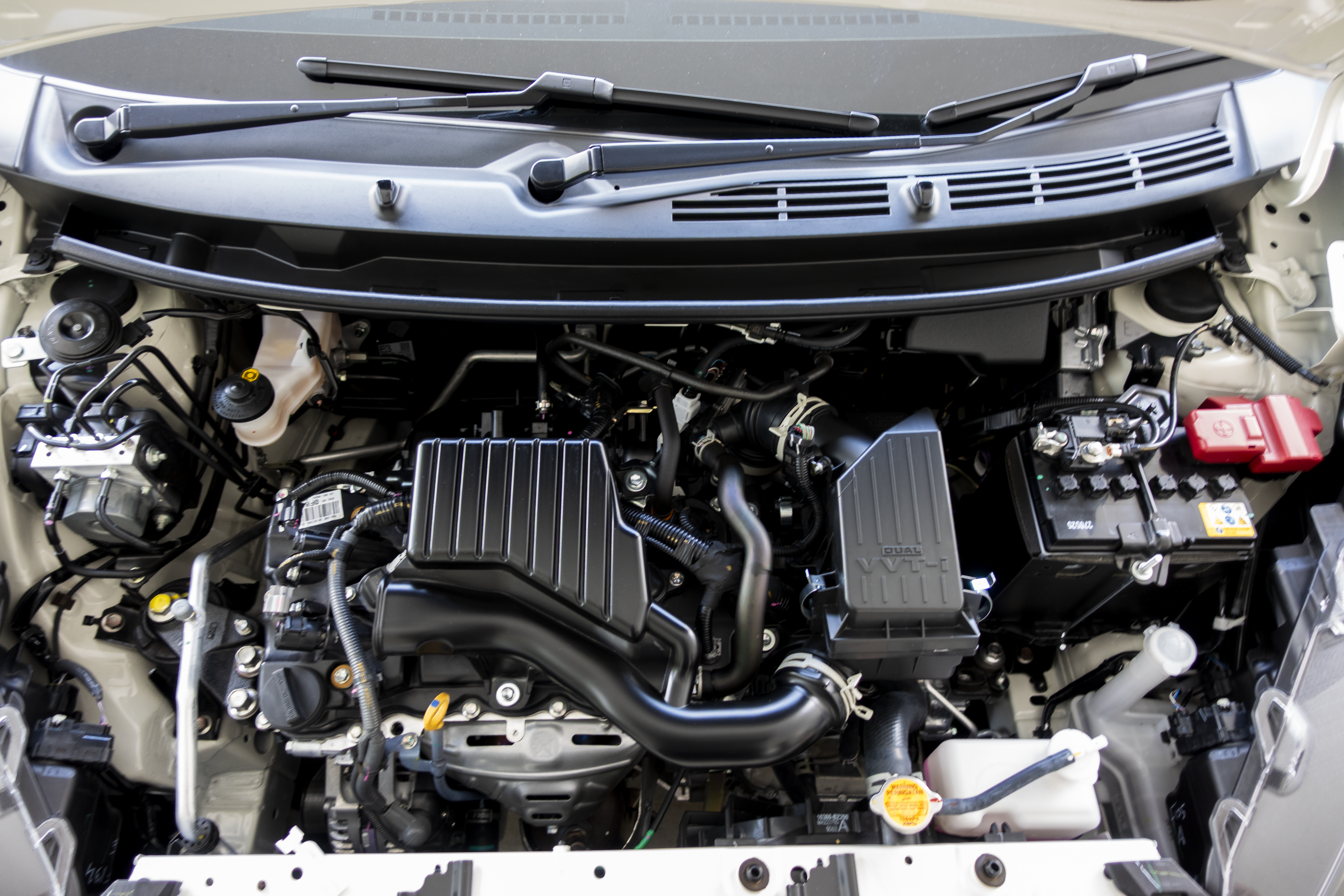 A car engine bay with various components including the air intake, battery, and fluid reservoirs.