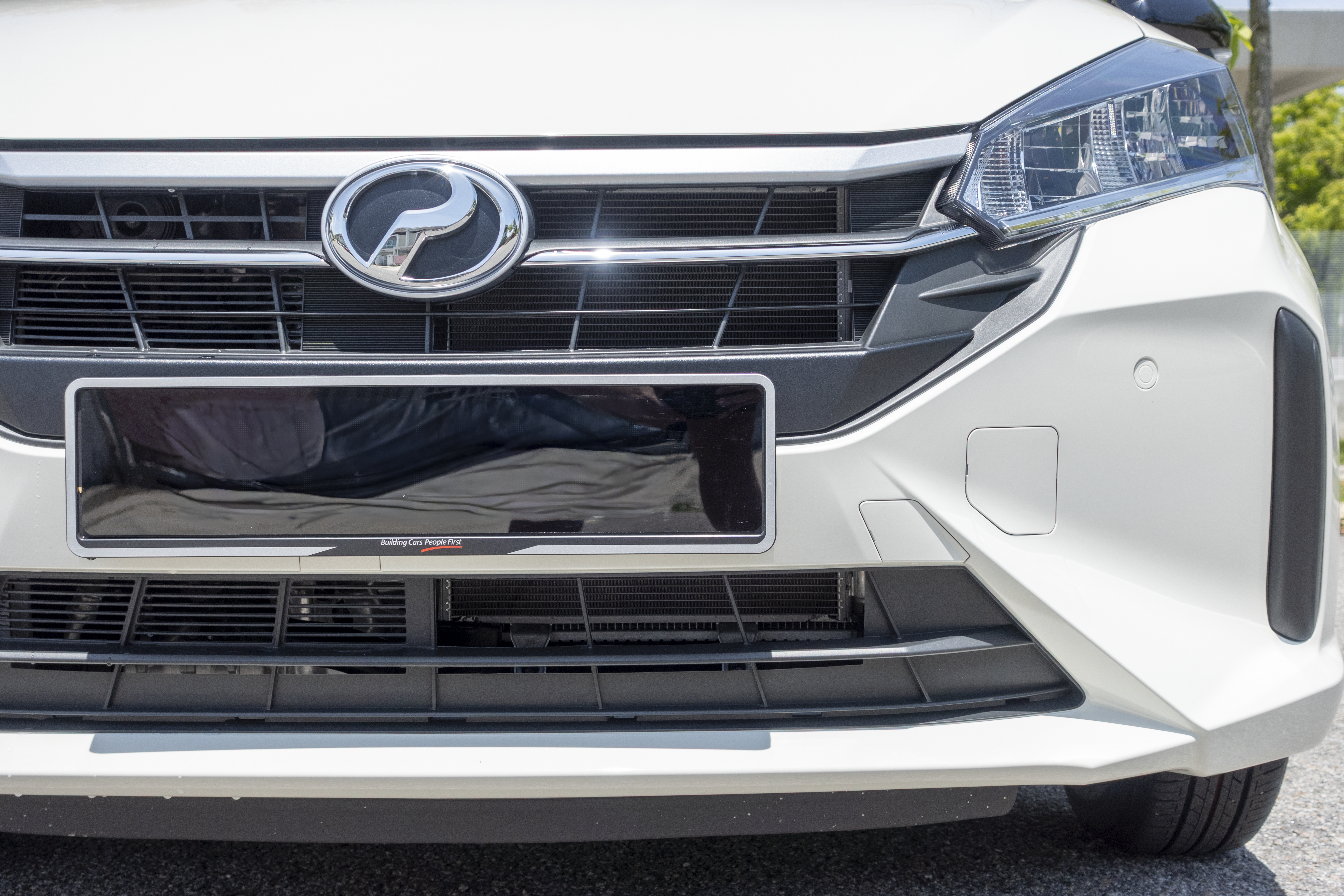 A white car features a distinctive logo on the grille, along with sleek headlights and a front license plate area.