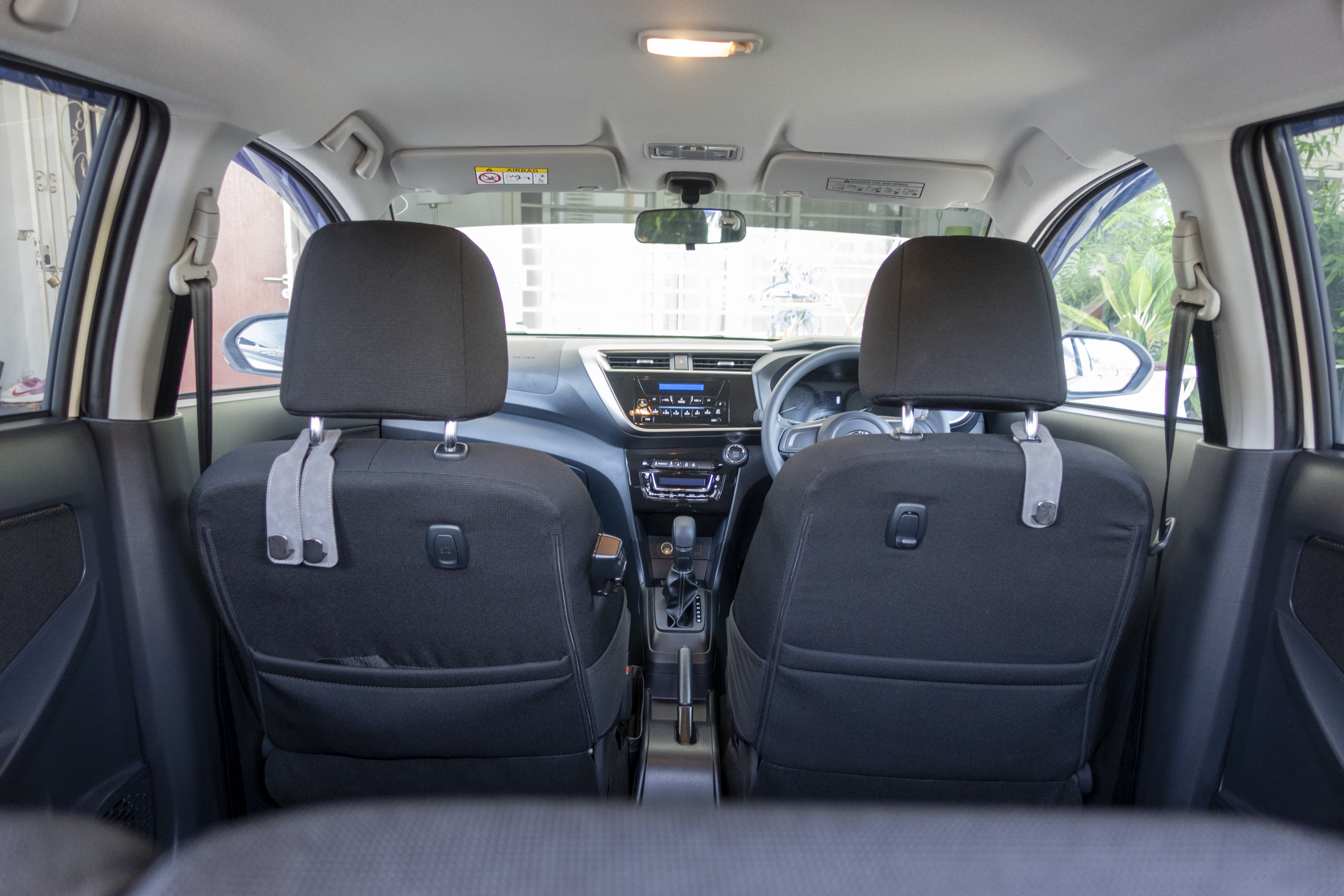 A view from the back seats of a car interior, showing the dashboard, steering wheel, and front seats.