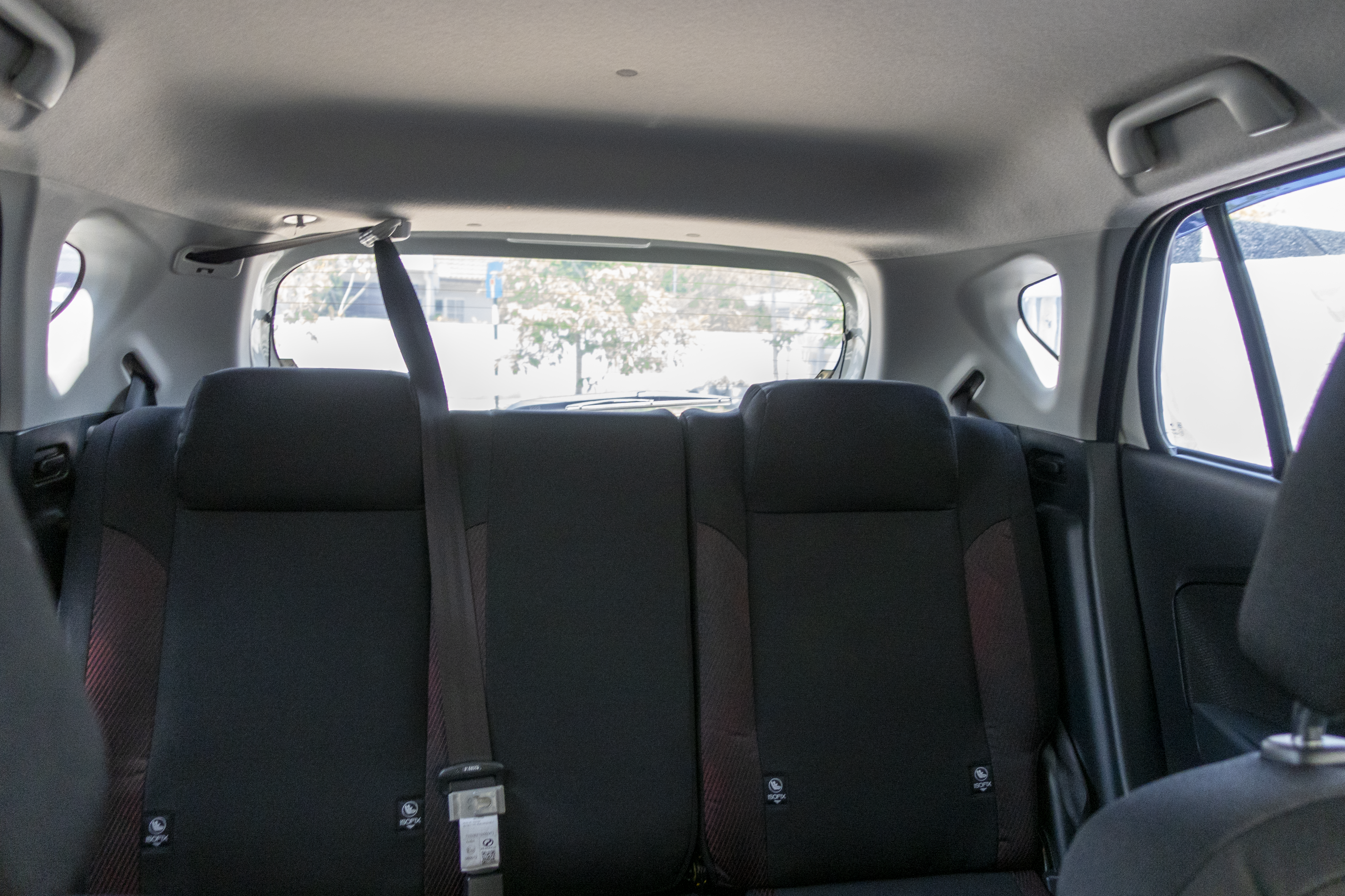 A view of the rear seats inside a car, showing seatbelts and the back window.