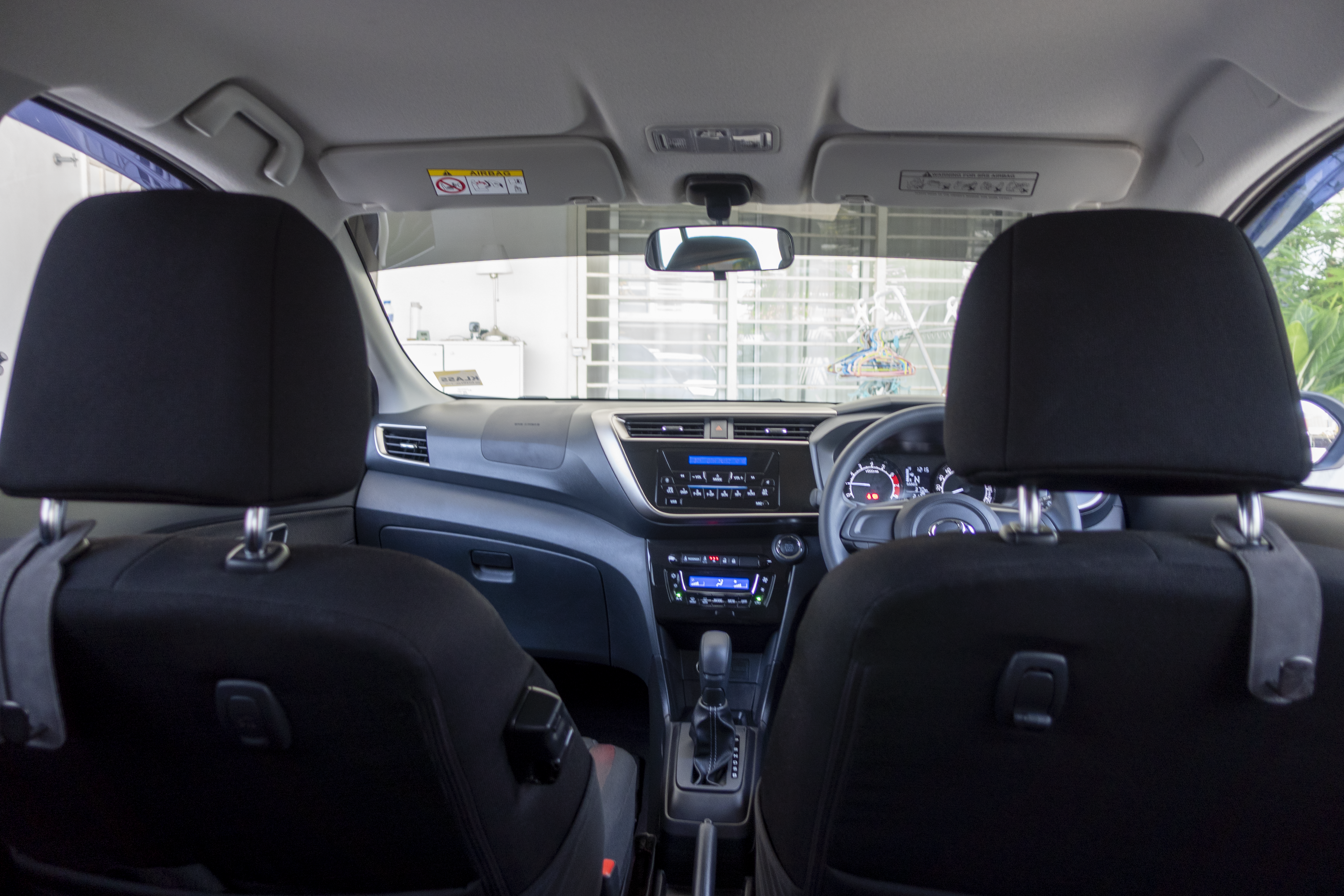 A car interior is shown from the back seat, highlighting the dashboard, steering wheel, and infotainment system.