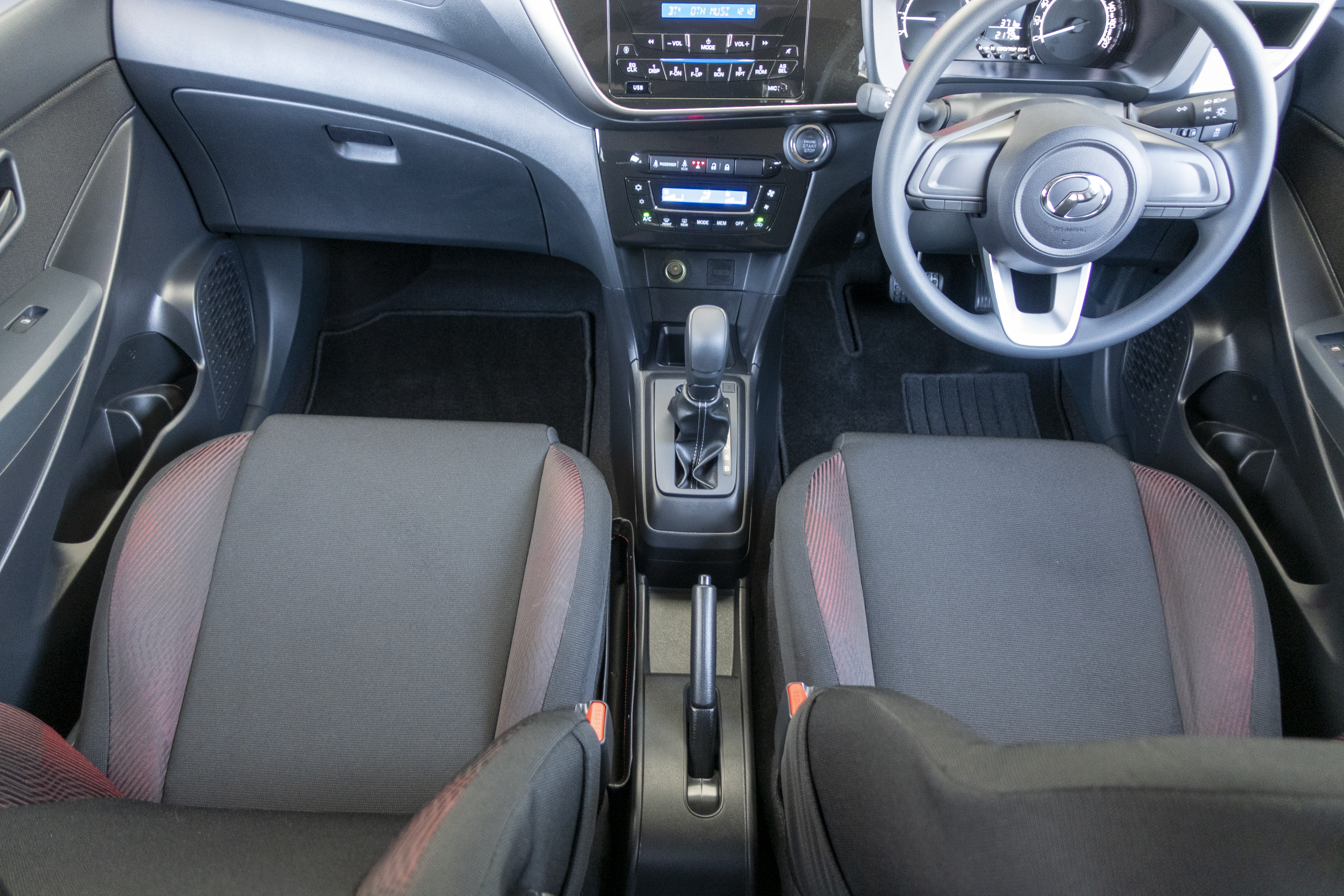 A car interior featuring two front seats, a steering wheel, and a central console with various controls.