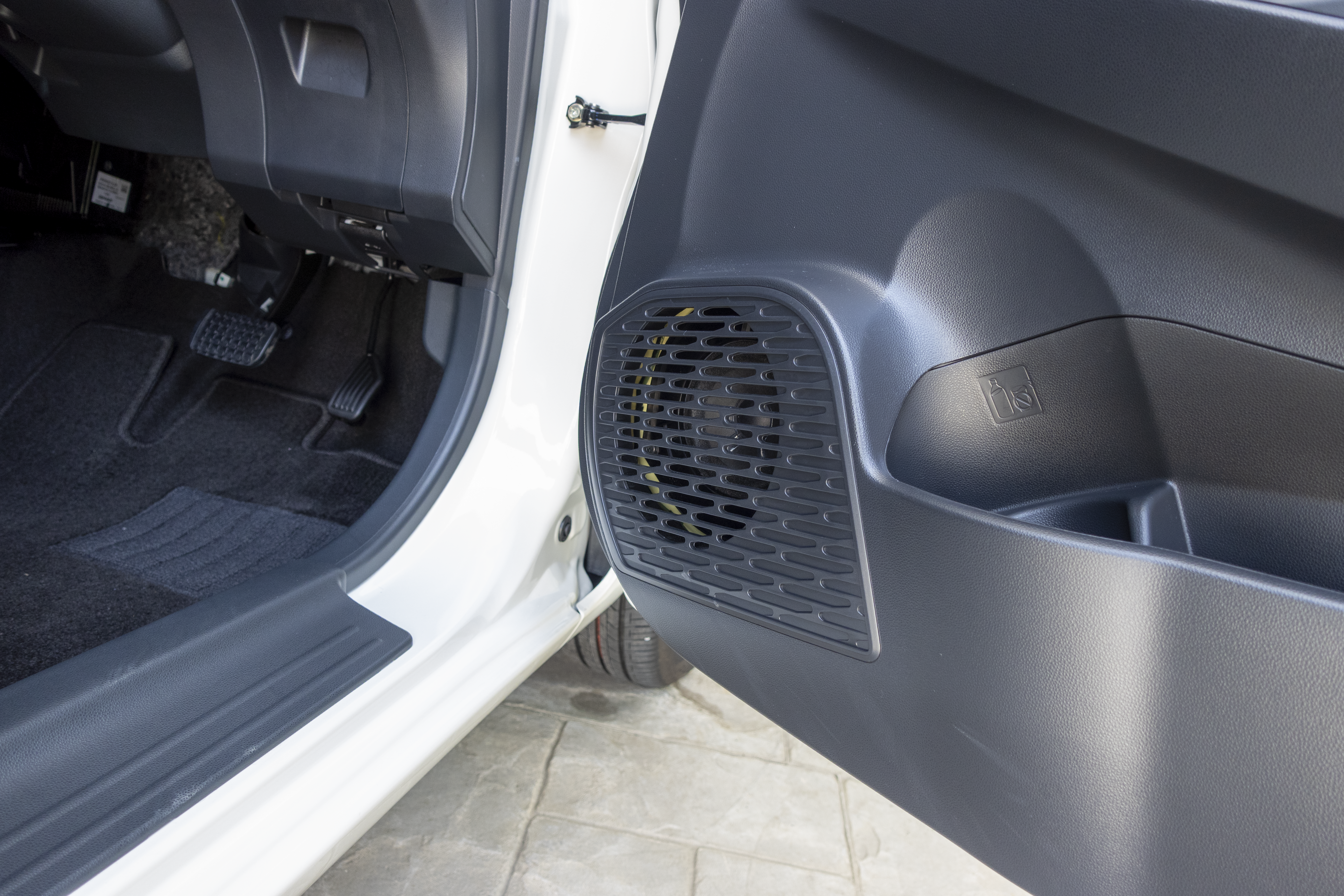 A car's interior is visible with an open door, featuring a speaker grill on the door panel.