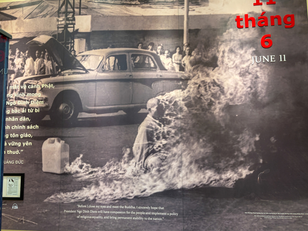 A person is set on fire in front of a car with its hood open, while a crowd watches from behind, depicting the self-immolation of Thich Quang Duc on June 11.