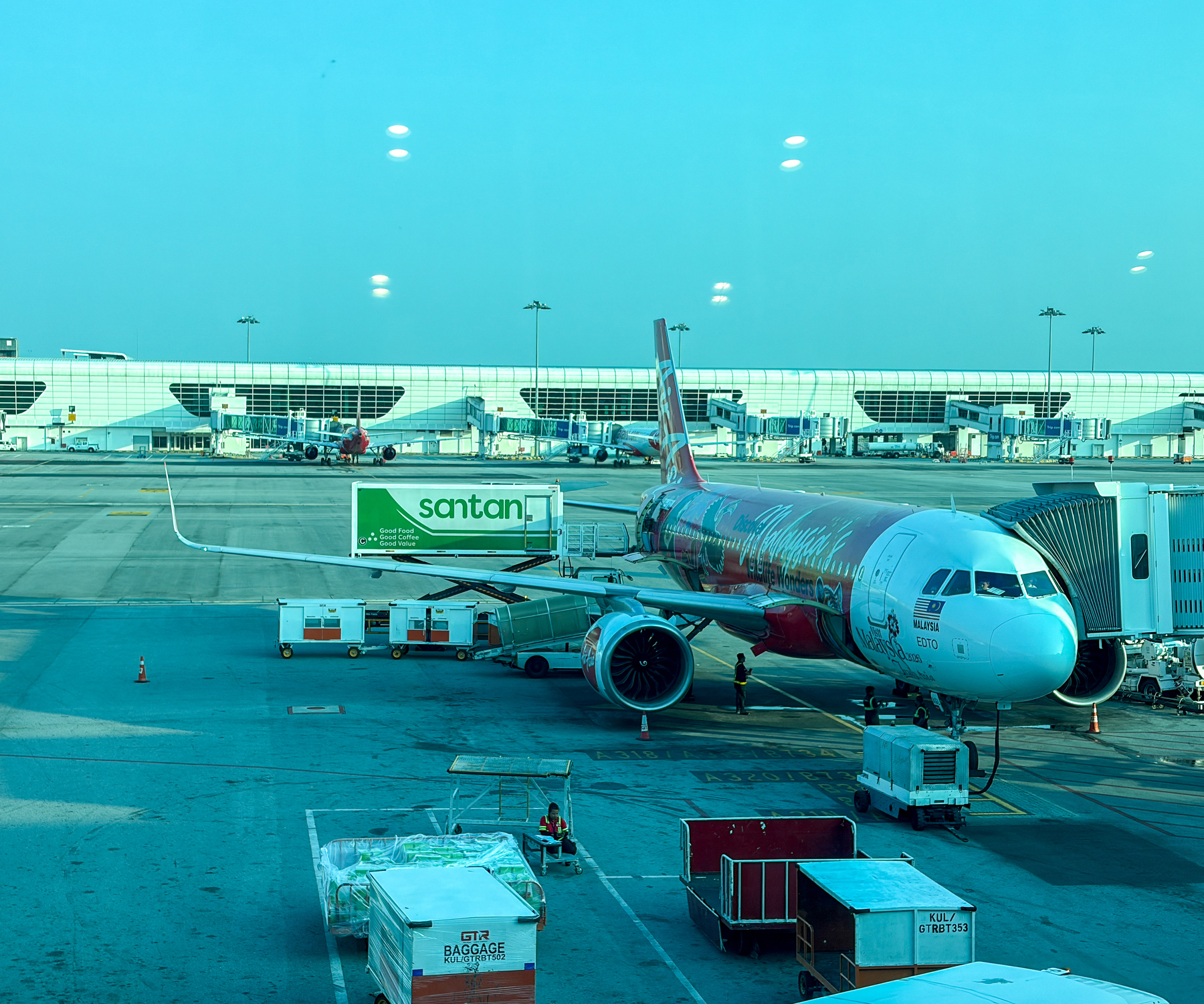 An airplane decorated with a colorful design is parked at the gate with various ground service vehicles around it at an airport.
