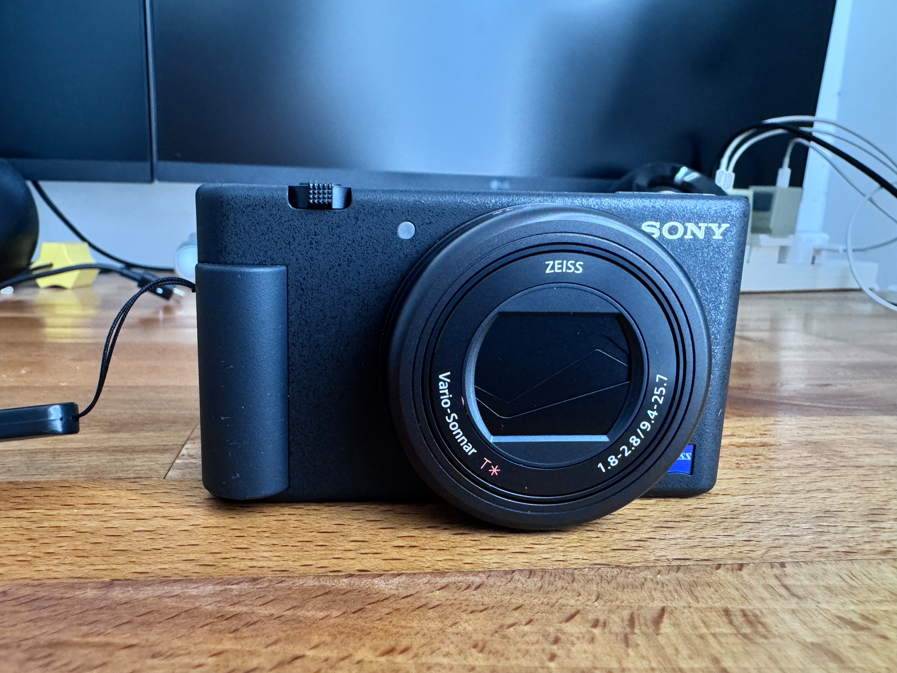 Auto-generated description: A black Sony camera with a Zeiss lens is placed on a wooden surface.