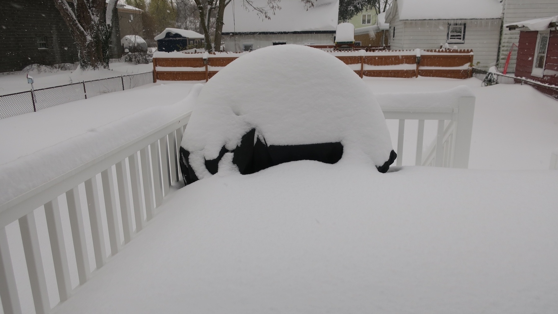 A heavy snowfall has covered a backyard deck and grill.