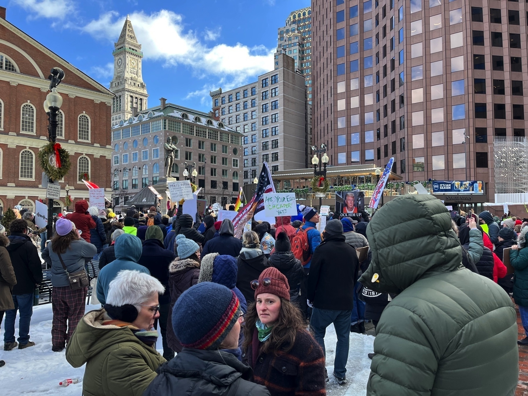 One sign has a picture of Donald Trump in an orange jumpsuit and says ”lock him up”. Another sign says ”are your eggs cheaper yet”. 