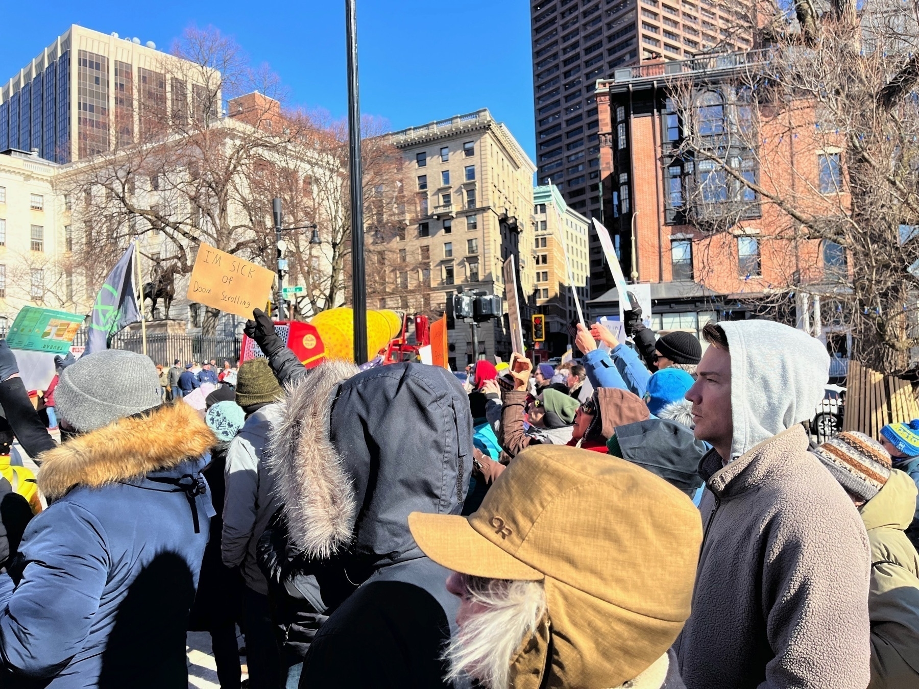 Lots of people. One has a sign that says ”I’m sick of doom scrolling”.