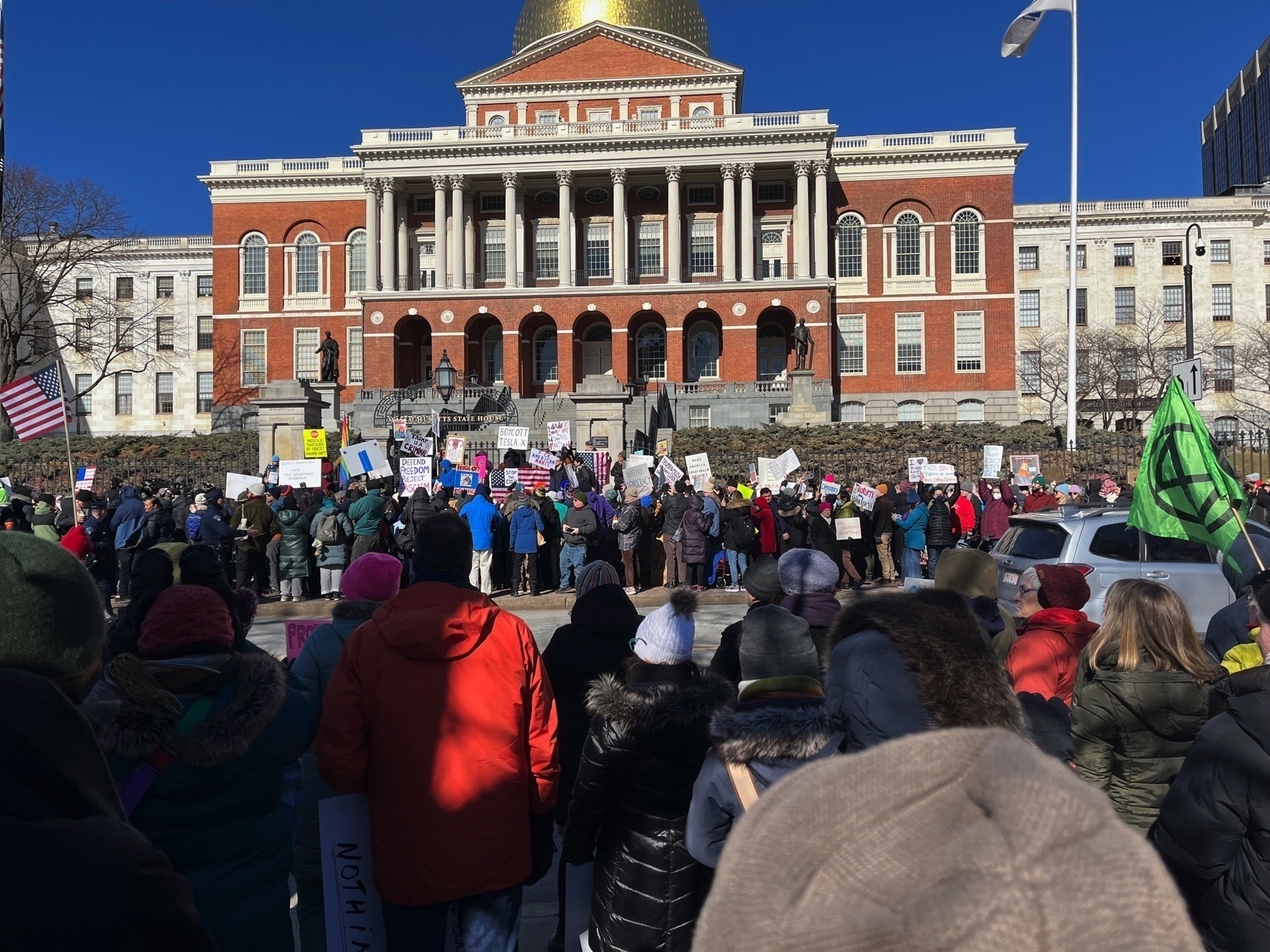 Big crowd with protest signs in front of the state house.