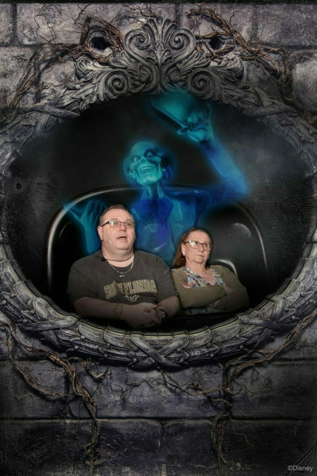 Two people on a theme park ride appear surprised while a ghostly figure looms behind them, set within a decorative frame.