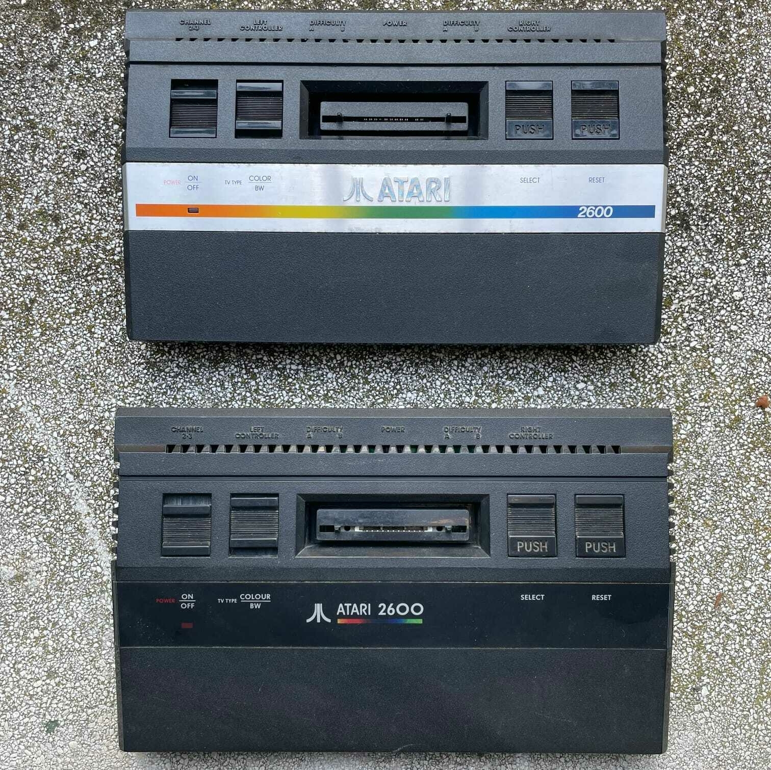 Mia foto personale dei due modelli di Atari 2600jr che possiedo, messi a confronto: In alto, il classico modello con frontalino in acciaio. Sotto, il modello Black Irish con una scocca tutta nera.