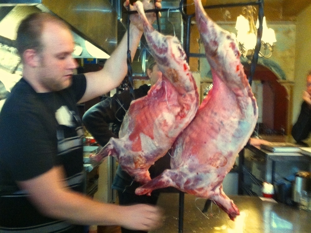 Connor the asador wires up the lamb to the frame.