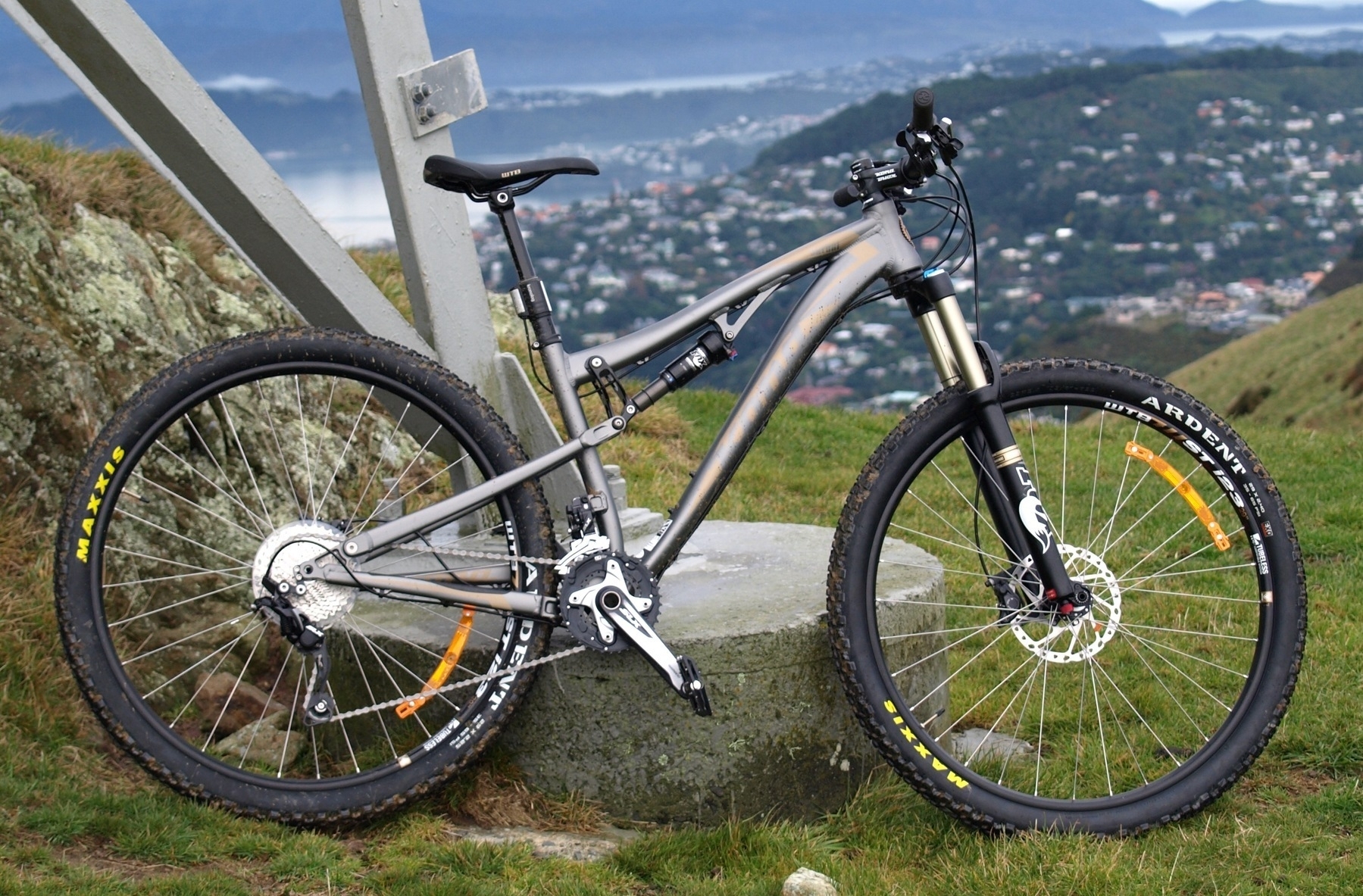 A new and shiny dual suspension mountain bike leans against a power pylon.