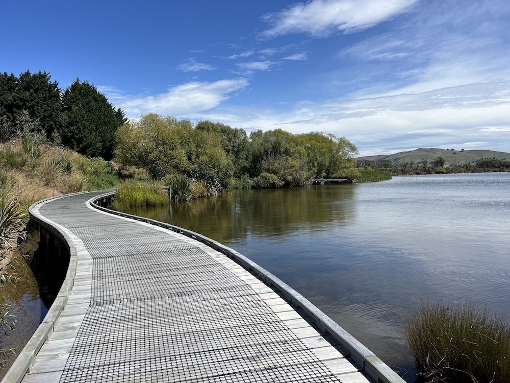 A timber boardwalk curves over a lake.